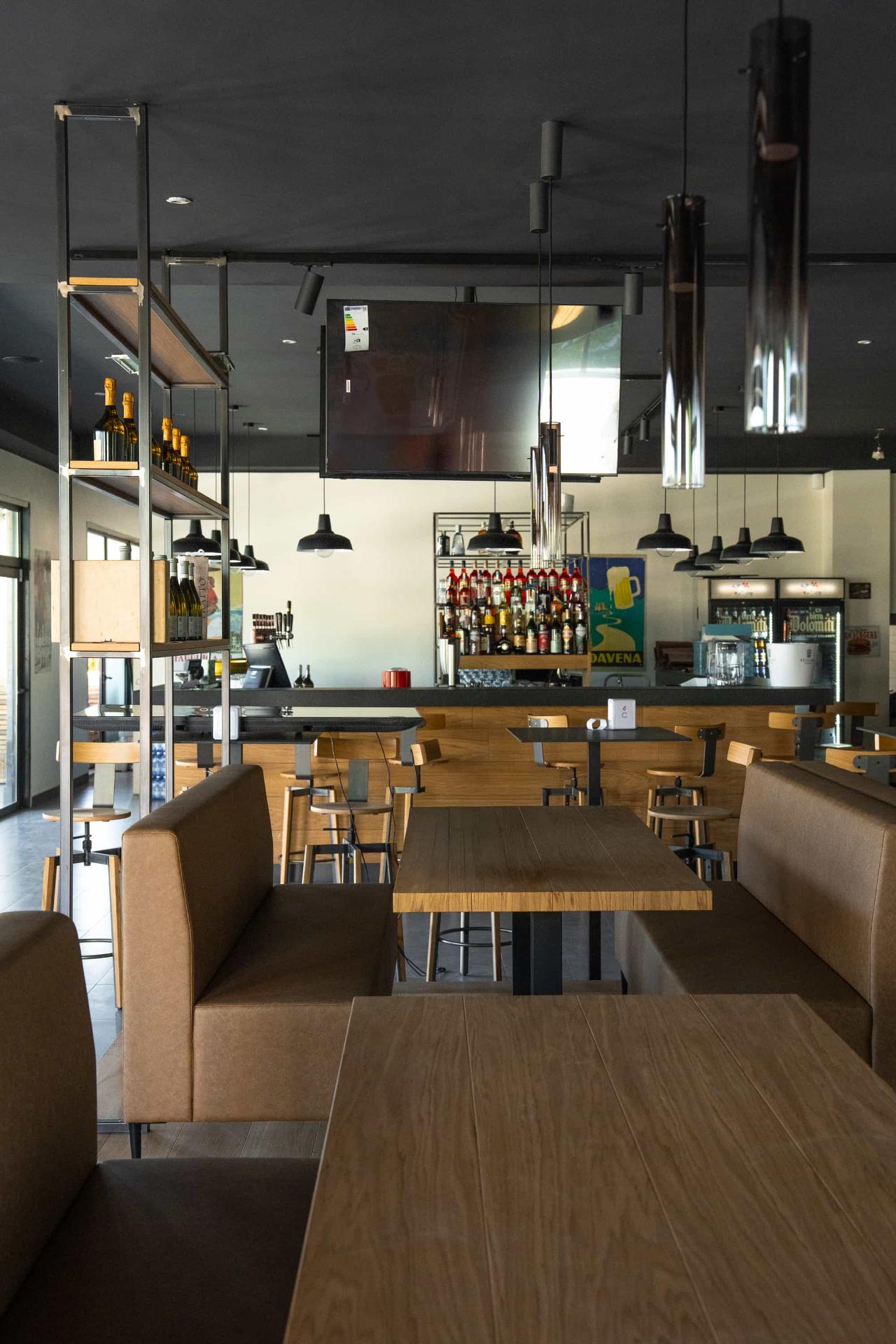Sala interna con bancone bar e tavoli in legno